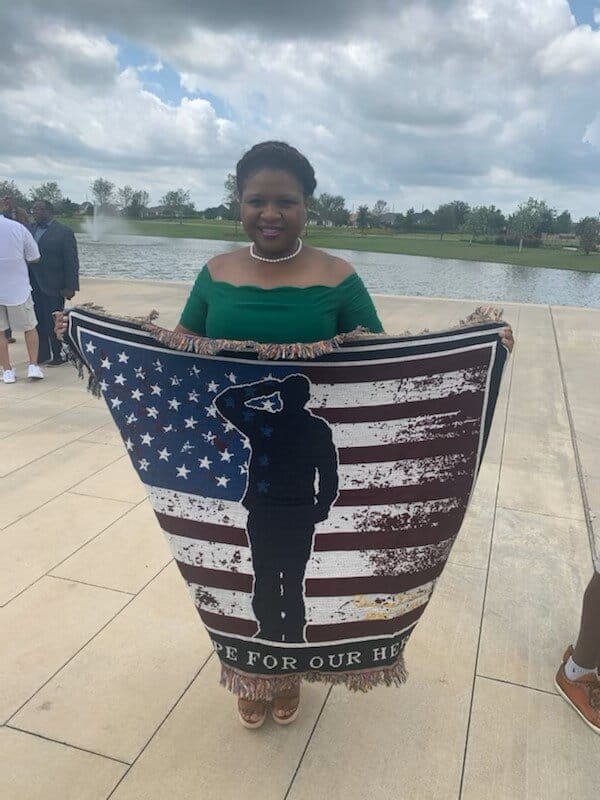 Marquette Greene-Scott holding a commemorative Hope for our Heroes flag blanket at a veterans recognition