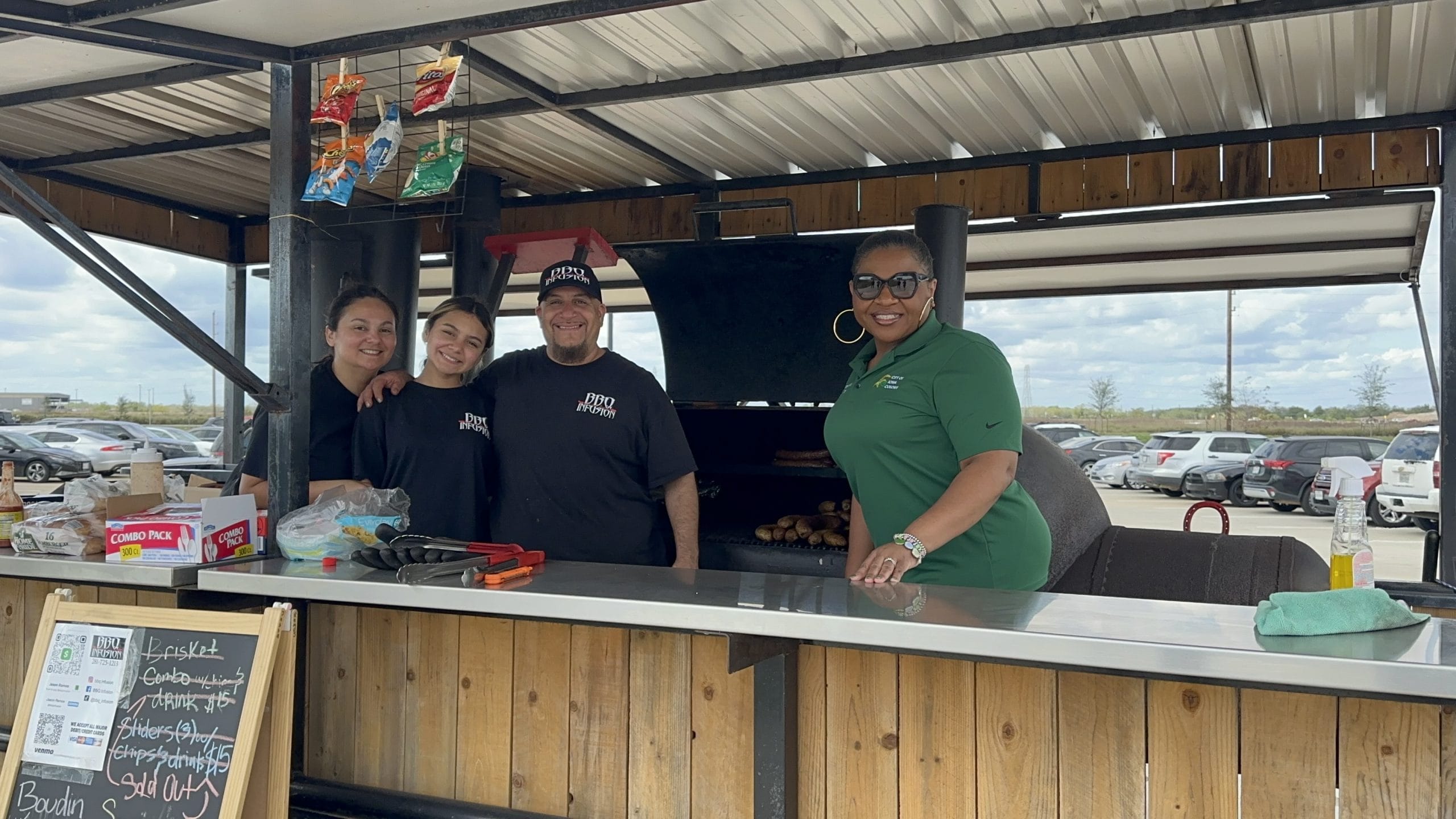Marquette Greene-Scott in a City of Iowa Colony polo shirt with the family running a local barbecue business